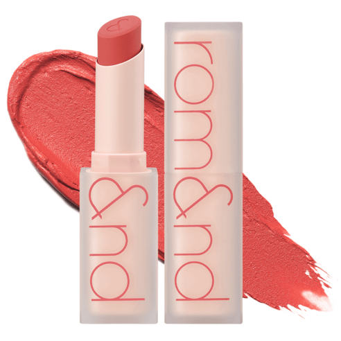 Matte coral lipstick with embossed heart shape on tip, beside matching cap and a swatch of intense color texture.