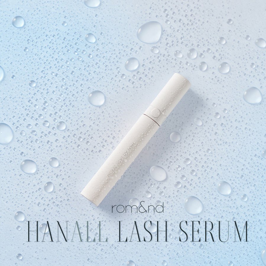 White sleek eyelash serum tube lying on a light blue surface with water droplets emphasizing hydration and lash strength
