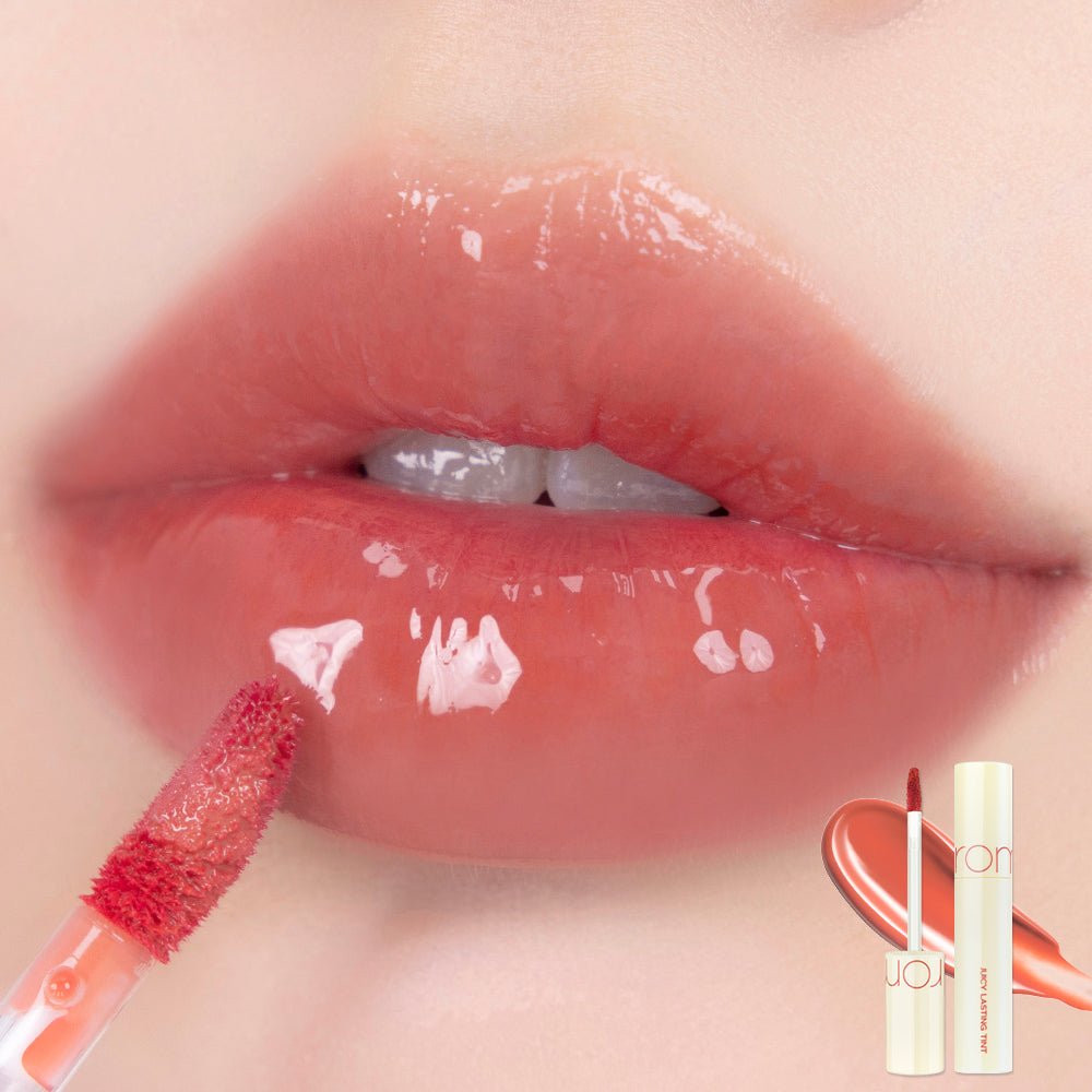 Close-up of glossy lips with a coral-tinted lip tint applicator applying smooth, long-lasting color finish.