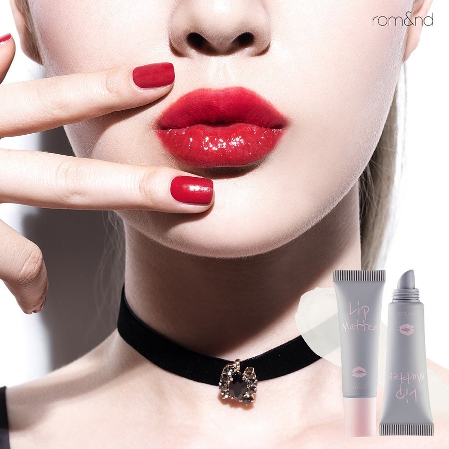 Close-up of lips with glossy red color and matching red nail polish, with lip product tubes displayed nearby