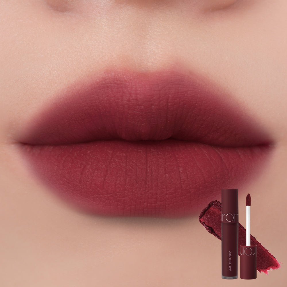 Close-up of lips wearing deep berry velvet tint with rom&nd weightless liquid applicator nearby