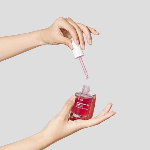 Hands holding Anua Niacinamide 10% + TXA 4% Dark Spot Correcting Serum 30ml with dropper dispensing serum.