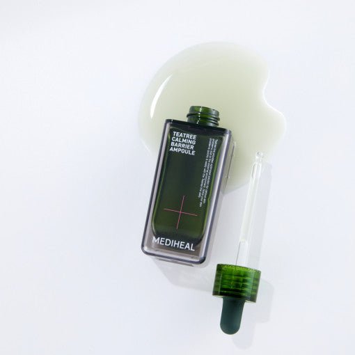 Dark green ampoule bottle with dropper and spilled clear liquid on white surface showing calming skincare product.