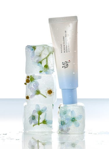 Blue and white tube of hydrating sun cream balanced on ice cubes with embedded small white and blue flowers