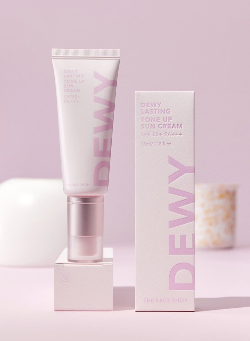 Light pink tube and box of tone-up sun cream with SPF50+ PA+++ on soft pink background with subtle decorative objects