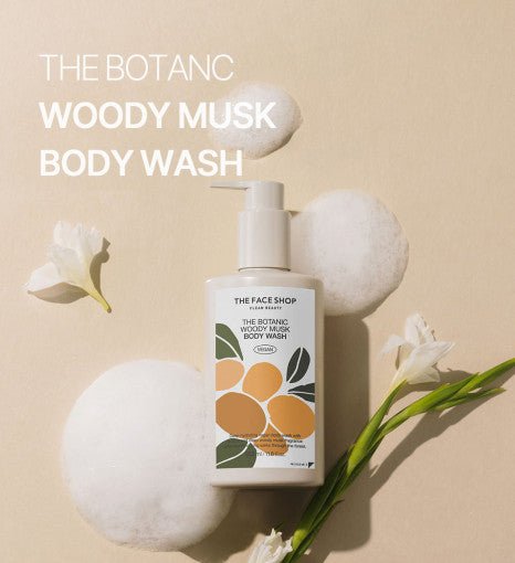 Pump bottle of woody musk body wash with foam bubbles and white flowers on soft beige background