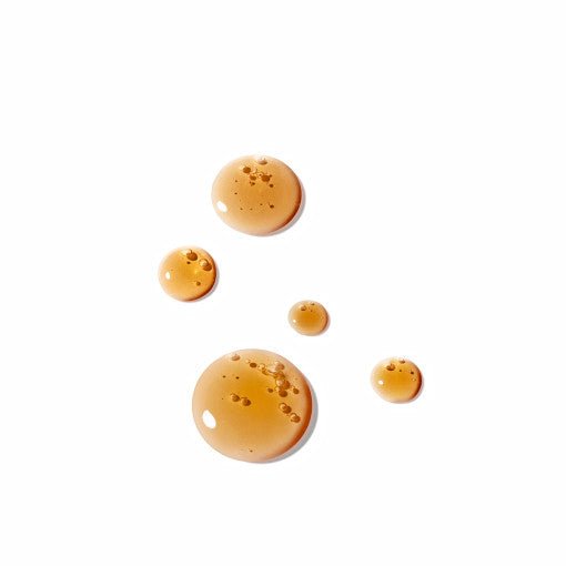 Amber serum droplets on white background highlighting smooth texture for fine lines treatment