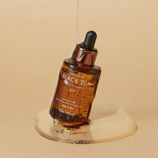 Amber dropper bottle of antioxidant-rich black tea oil with smooth liquid pooling on beige surface