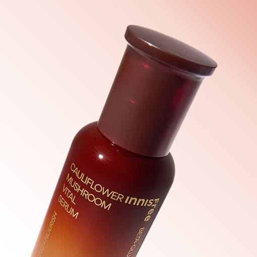 Amber bottle of serum featuring cauliflower mushroom extract with moisture boost benefits on soft gradient background