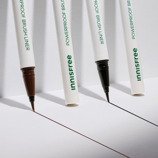 Two innisfree Powerproof Brush Liners with precise brush tips drawing sharp brown and black lines on white surface
