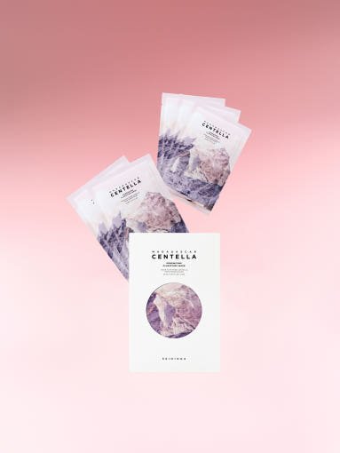 Set of five skincare mask sachets with pastel mountain design and white outer packaging on pink background