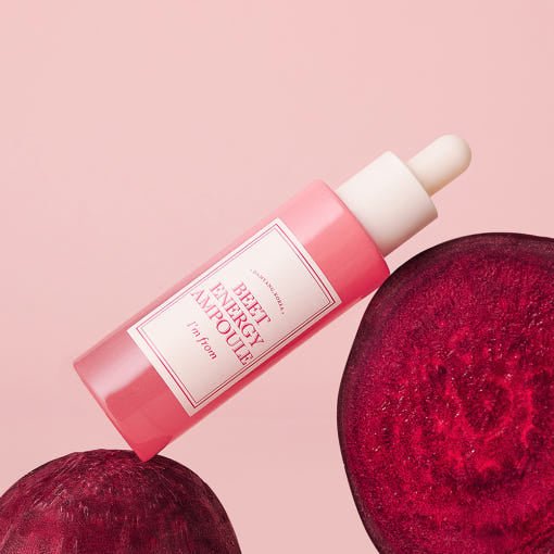 Pink glass dropper bottle of hydrating ampoule displayed with sliced beetroot on soft pastel background