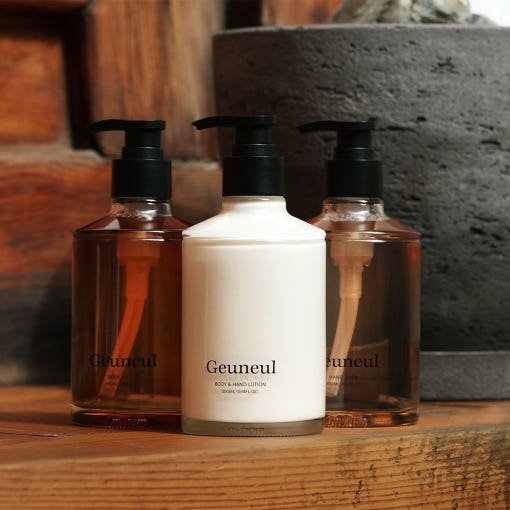 Three pump bottles of lotion with the central white bottle labeled Geuneul offering instant hydration on a wooden surface