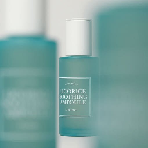 Frosted blue glass dropper bottle of soothing ampoule with white cap on a soft teal background