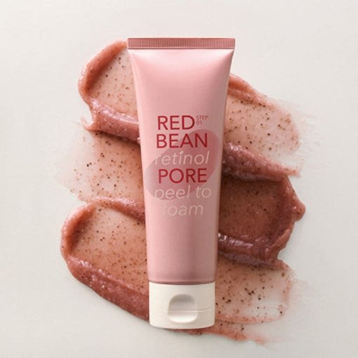 Pink tube of retinol pore peel to foam cleanser on beige surface with textured exfoliating gel swatches behind it