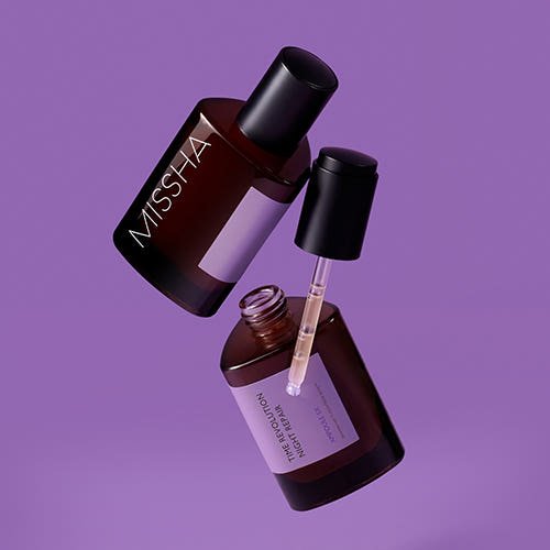 Two dark amber glass ampoule bottles with black caps and purple labels for deep hydration on a purple background
