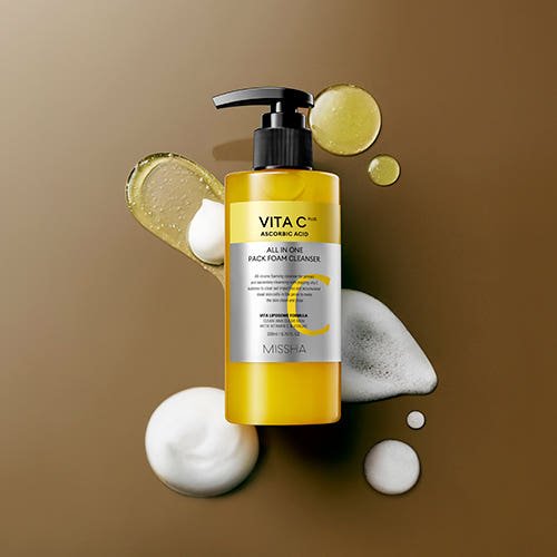 Yellow pump bottle of vitamin C foam cleanser with ascorbic acid and foam texture on a brown surface background