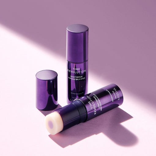 Purple cylindrical balm stick container with brightening night repair ampoule balm on a soft pink background