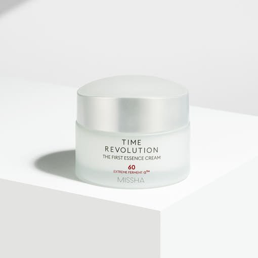 Frosted glass jar of rich hydrating essence cream with a silver lid on a minimalist white surface