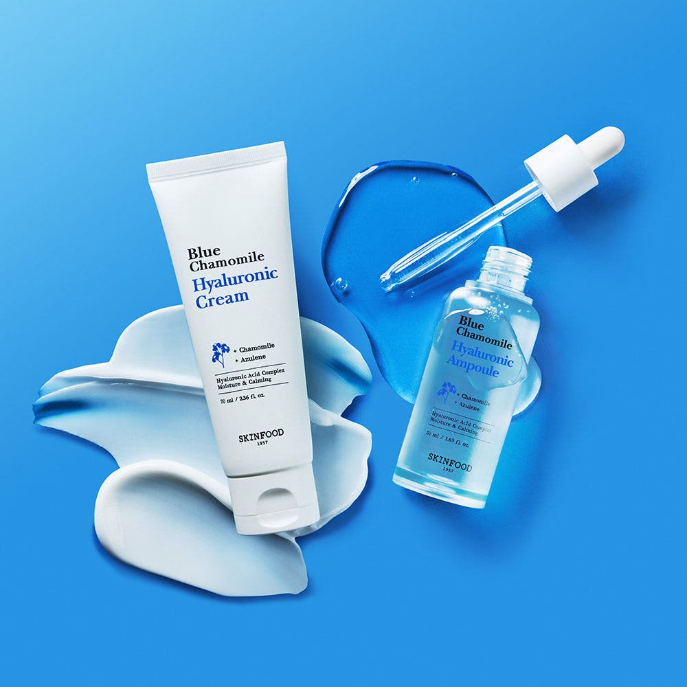 Clear blue dropper bottle of moisturizing ampoule with white hyaluronic cream spread on blue background