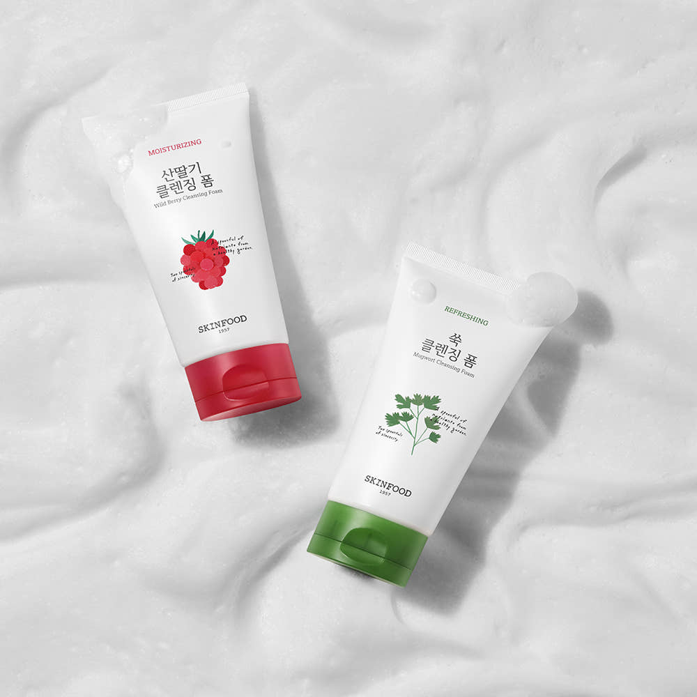 Two tubes of moisturizing facial cleansing foam with red and green caps, placed on white foam background