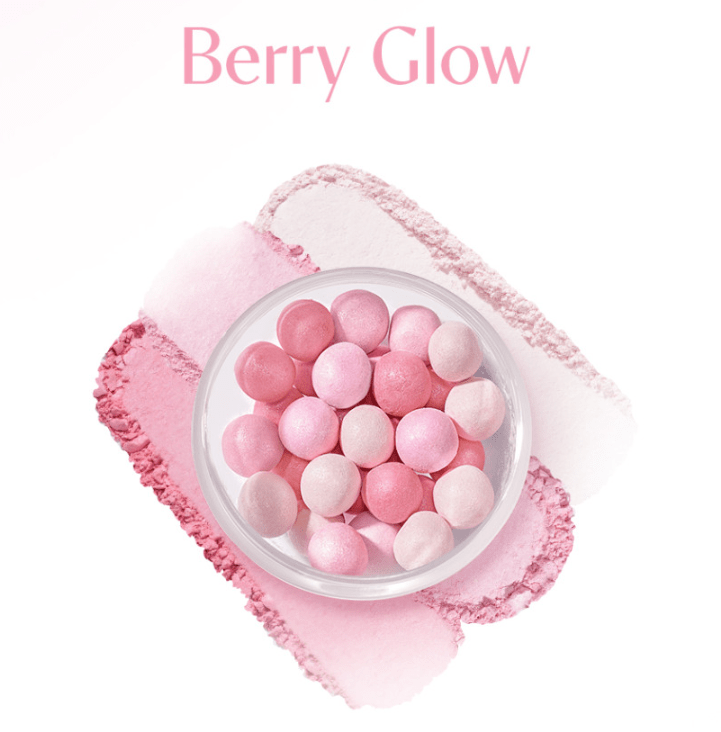 Clear container filled with assorted pink powder pearls on layered pink powder swatches, highlighting illuminating effect
