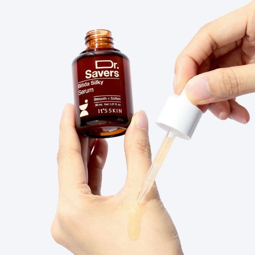 Hands holding amber dropper bottle dispensing light serum on skin for stronger barrier care ritual