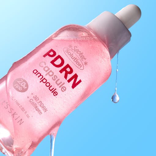 Pink ampoule bottle with dropper releasing a droplet against a bright blue background for skin regeneration care