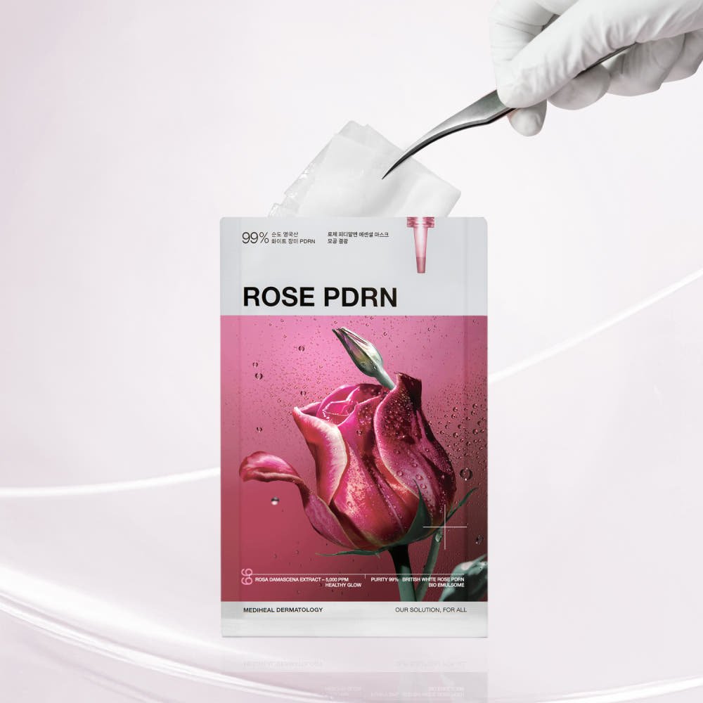 Hand removing a white sheet mask from pink-packaged skincare pouch featuring a close-up rose image