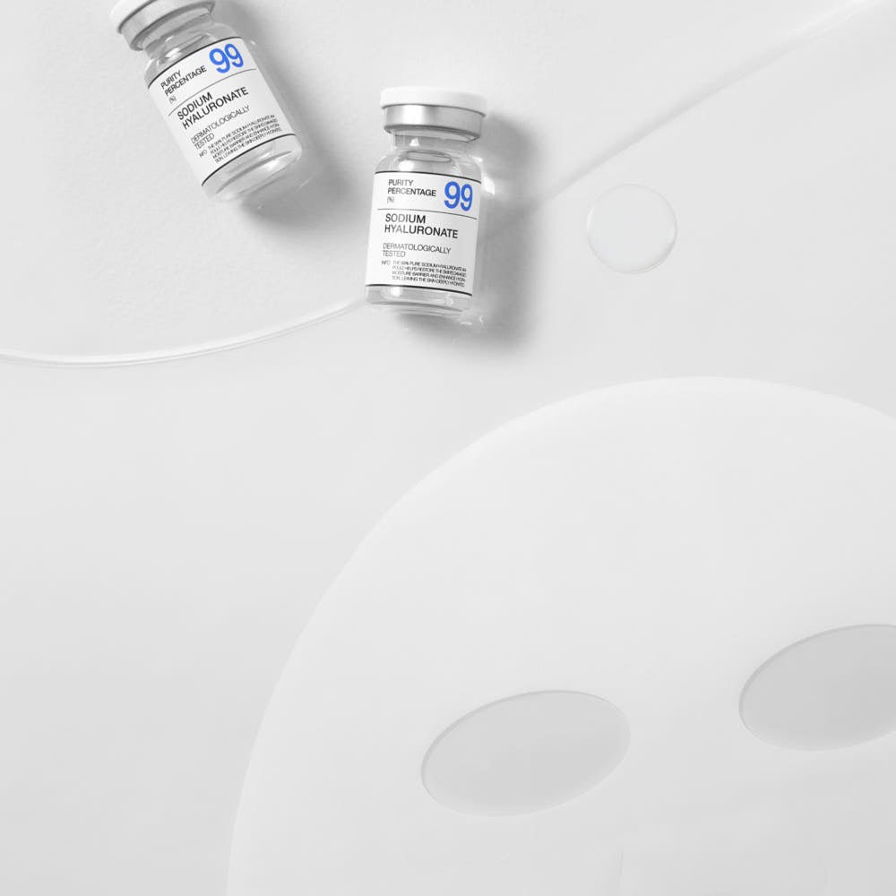 Two clear vials labeled sodium hyaluronate with a translucent sheet mask and serum drops on white surface