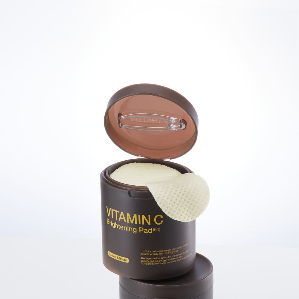Open brown jar with textured brightening pad lifted, showing skincare product for vitamin C brightening benefits