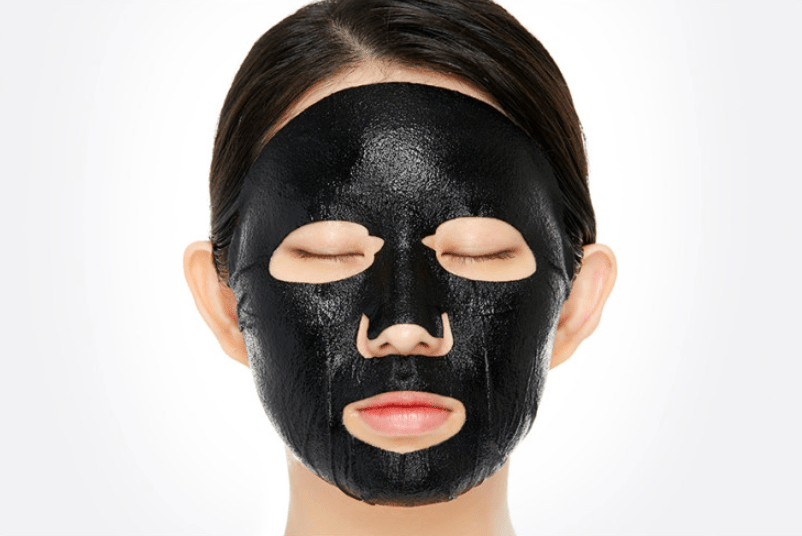 Person with smooth black pore-minimizing face mask applied, eyes closed against white background