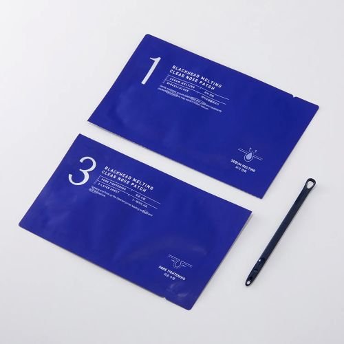 Two blue sachets labeled for blackhead melting clear nose care and a small black skincare spatula on white background