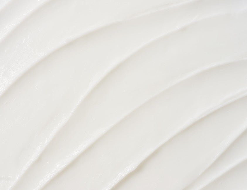 Smooth white cream texture with gentle curved spread pattern in soft lighting background
