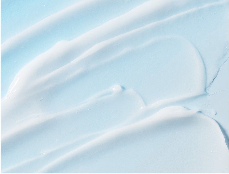 Smooth, creamy texture of a nourishing hair ampoule formula spread across a light blue background surface