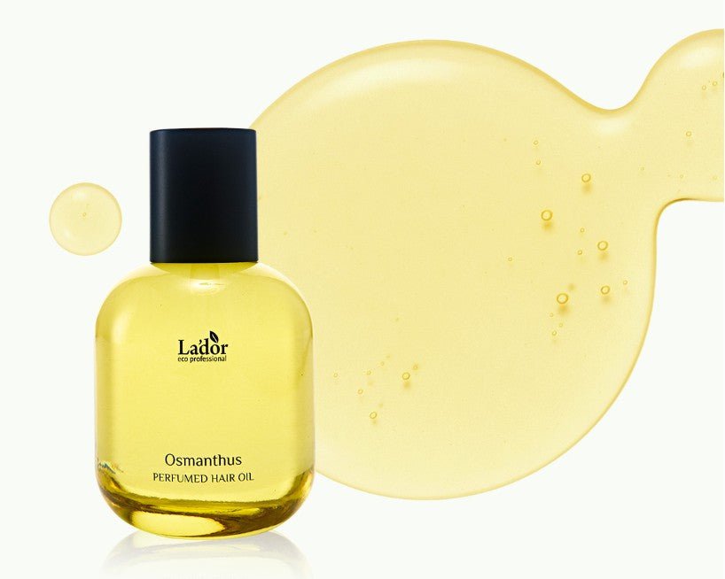 Clear bottle of golden yellow hair oil with black cap next to spilled oil drop showcasing smooth, lightweight texture
