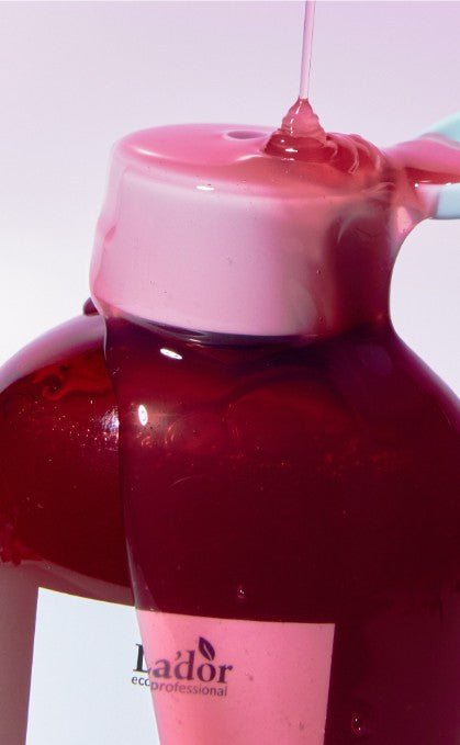 Close-up of glossy pink shampoo being poured over a dark red bottle cap promoting healthy scalp care.