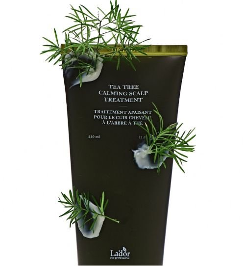 Dark green tube of scalp treatment with fresh tea tree sprigs and creamy product on the surface for soothing relief.