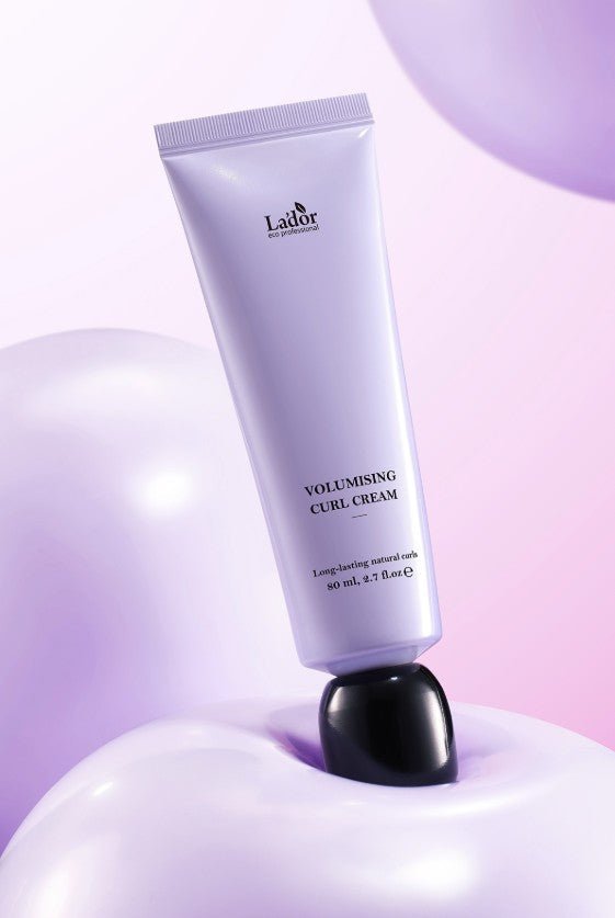 Lavender tube of curl cream balanced on shiny spherical objects in soft purple and pink lighting background