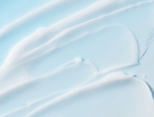 Smooth light blue nourishing hair treatment cream spread across a surface with subtle texture variations