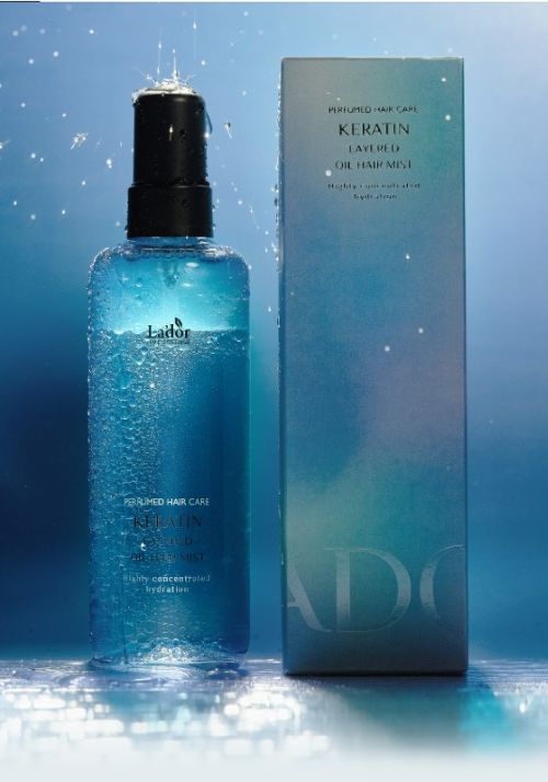 Blue bottle of keratin hair mist with black pump beside matching gradient box, water droplets adding moisture effect.