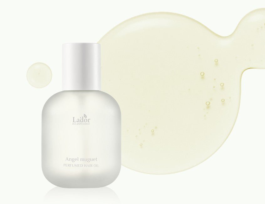 Frosted bottle of perfumed hair oil next to a translucent golden liquid drop with small air bubbles visible inside