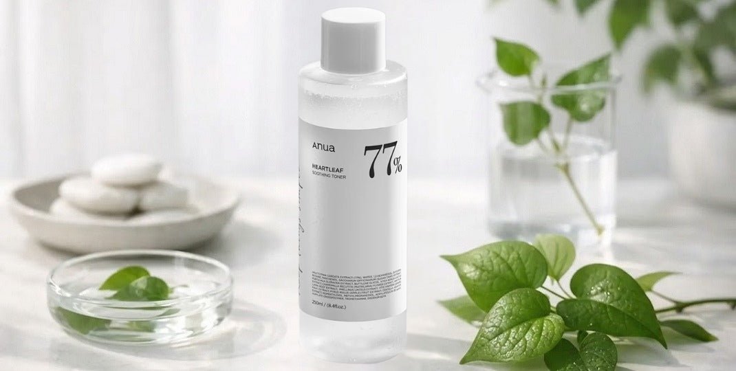 White skincare bottle labeled 77 percent with green leaves glass dish and stacked stones