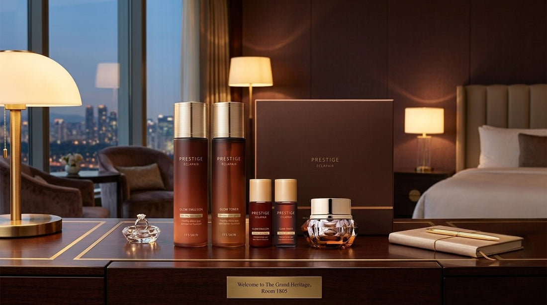 Prestige Eclapair glow toner, emulsion, serums and cream arranged on a hotel desk with warm lamp lighting and city skyline in background.