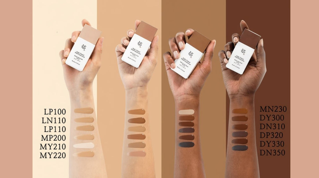 Four arms of varying skin tones with matching foundation swatches and compact foundations held above each arm.