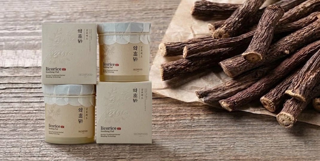 Four beige jars and boxes arranged beside dried licorice roots on a weathered wooden surface