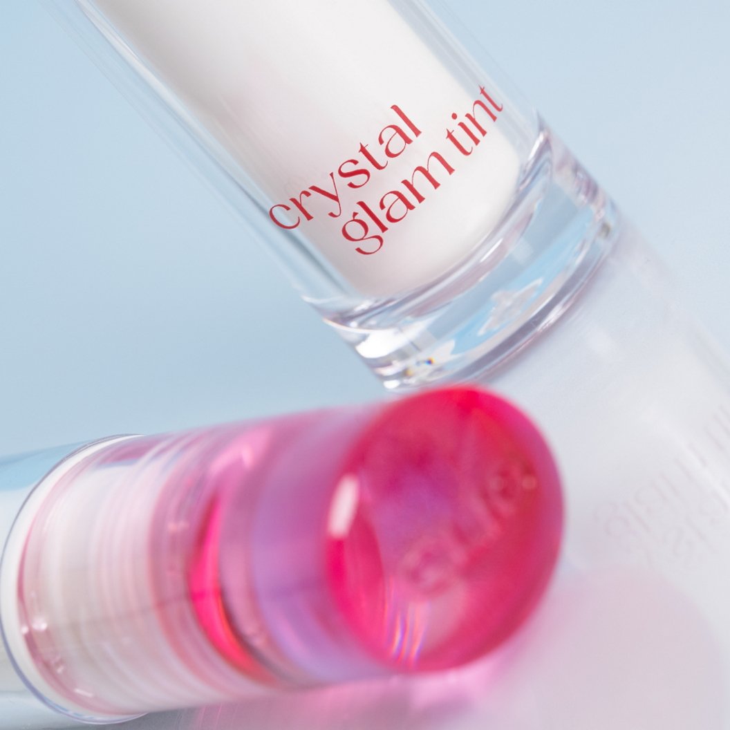 Pink lip tint with 'crystal glam tint' text on a light blue background