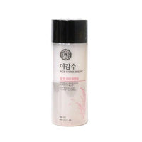 Opaque bottle of gentle makeup remover for lips and eyes with black cap and delicate rice illustration on white background