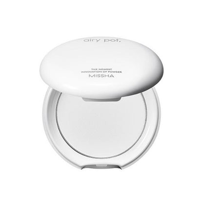 White compact powder case with translucent pressed powder and minimal branding on top against white background