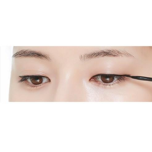 Close-up of eyes with smooth skin applying precise black liquid eyeliner along the upper lash line for a sharp finish